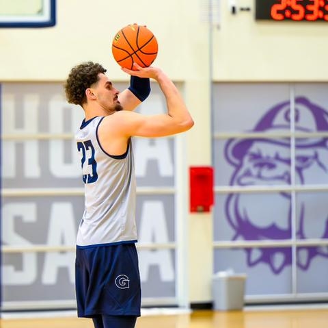 Branded window film on practice court windows is backdrop to a Georgetown University basketball taking a jump shot.