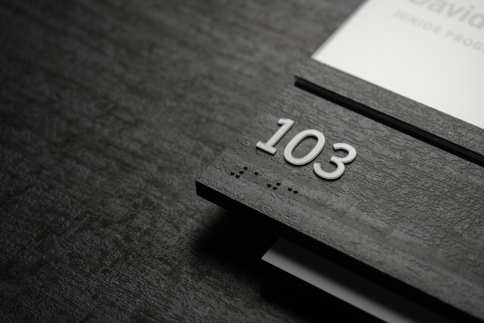 Detail photo of an interior Room ID sign with updateable insert and a dark wood textured laminate